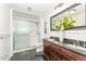Bathroom featuring double vanity, tiled floors, wainscotting, and glass door shower at 4832 Brookhaven Dr, Raleigh, NC 27612