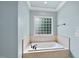 A bathtub under a window provides a relaxing space in this lovely bathroom at 5217 Roswellcrest Ct, Apex, NC 27539