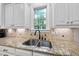 Bright kitchen featuring a stainless steel sink and granite counters with a large window overlooking mature trees at 5217 Roswellcrest Ct, Apex, NC 27539
