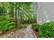 Paver path alongside the home featuring lush landscaping, rock accents, and mature trees at 5217 Roswellcrest Ct, Apex, NC 27539