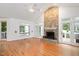 Bright living room featuring hardwood floors, a stone fireplace, and large windows at 5241 Mill Dam Rd, Wake Forest, NC 27587