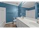 Full bathroom with double sinks, tile floors, and blue walls at 5310 Echo Ridge Rd, Raleigh, NC 27612