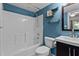 Bathroom features a tub and shower combo, blue walls and a dark vanity with shelving for a stylish and functional space at 5310 Echo Ridge Rd, Raleigh, NC 27612