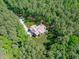 Aerial view of a modern farmhouse with attached three car garage surrounded by lush green forest at 59 Mill Rd, Pittsboro, NC 27312