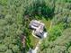 An aerial view of a home with a three car garage on a manicured lawn surrounded by dense green trees at 59 Mill Rd, Pittsboro, NC 27312