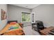 Bright bedroom features a large window, gray chair, and bed with orange comforter at 59 Mill Rd, Pittsboro, NC 27312