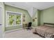 Bedroom with desk, green accent wall, bed, and large window overlooking trees at 59 Mill Rd, Pittsboro, NC 27312
