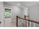 Upstairs hallway with wooden railing leading to a room with a gray wall and window at 59 Mill Rd, Pittsboro, NC 27312