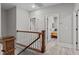 Upstairs hallway with wood banister leads to bedroom with an orange comforter and gray walls at 59 Mill Rd, Pittsboro, NC 27312