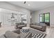Open concept living room with gray sofas and black and white rug flows into the kitchen at 59 Mill Rd, Pittsboro, NC 27312