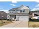 Charming two-story home with a front-facing two-car garage, a porch with a white railing, and manicured landscaping at 59 Nevada Ct, Clayton, NC 27527