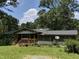 Quaint single story home with a covered front porch and metal roof surrounded by mature trees on a sunny day at 6010 Bonlee Bennett Rd, Bear Creek, NC 27207