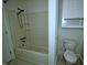 Bathroom with white tiled shower-tub combo, toilet, and white wall cabinet at 6017 Whitaker Ln, Raleigh, NC 27603