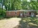 Charming brick home featuring a well-maintained lawn and a screened in porch in a tranquil, wooded setting at 6017 Whitaker Ln, Raleigh, NC 27603