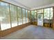 View of the enclosed sunroom with transparent wall panels, brick base, and exterior door at 6017 Whitaker Ln, Raleigh, NC 27603