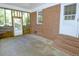 Spacious sunroom with brick walls, concrete floor, and two exterior doors at 6017 Whitaker Ln, Raleigh, NC 27603