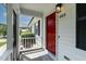 A welcoming red front door is showcased with a screened-in porch and a view of landscaped surroundings at 605 Larchwood Dr, Durham, NC 27713