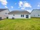 Green backyard with house featuring vinyl siding, window, and sliding door under cloudy, blue sky at 631 Southwick Pl, Mebane, NC 27302