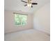 Bright bedroom featuring a ceiling fan, plush carpet, and a sunlit window overlooking lush greenery at 7616 Satinwing Ln, Raleigh, NC 27617