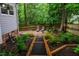 Backyard featuring a stone patio with seating, surrounded by well-maintained landscaping and mature trees at 8 Wexford Dr, Durham, NC 27713