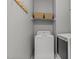Functional laundry room with washer, dryer, upper shelves with storage baskets, and a coat rack at 8724 Deerland Grove Dr, Raleigh, NC 27615