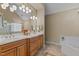 Main bathroom featuring a double sink vanity with wood cabinets, a large mirror, and tile flooring at 8724 Deerland Grove Dr, Raleigh, NC 27615