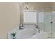 Main bathroom with soaking tub, glass shower, a chandelier, and a window at 8724 Deerland Grove Dr, Raleigh, NC 27615