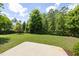 Well-maintained backyard with mature trees, a concrete patio, and lush green grass at 937 Sedgefield Park Ln, Cary, NC 27519