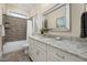 Well-lit bathroom featuring a granite countertop vanity, decorative mirror, and shower with stylish tiling at 937 Sedgefield Park Ln, Cary, NC 27519