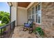 Cozy front porch with stone flooring, rocking chair, and classic railing, perfect for relaxing outdoors at 937 Sedgefield Park Ln, Cary, NC 27519