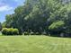 Large grassy backyard with mature trees, landscaping, a swing set and playhouse at 95 Live Oak Dr, Louisburg, NC 27549