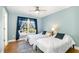Bright bedroom features two twin beds, hardwood floors, ceiling fan, and a large window with blue curtains at 101 Rainbow Dr, Carrboro, NC 27510