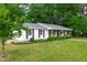 Beautiful white brick home with lush landscaping, dark shutters, and inviting front porch at 102 Lake Dr, Wendell, NC 27591