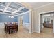 Bright dining room featuring a coffered ceiling, stylish chandelier, and views into the adjacent living area at 105 Blue Prince Trl, Holly Springs, NC 27540