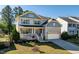 Inviting two-story home with stone accents, front porch, and professionally landscaped front yard at 105 Blue Prince Trl, Holly Springs, NC 27540