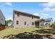 Rear exterior view of the house with a screened porch, spacious yard, and clean landscaping at 105 Blue Prince Trl, Holly Springs, NC 27540