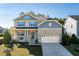 Charming two-story home boasts stone accents, gray siding, manicured lawn, and a welcoming covered front porch at 105 Blue Prince Trl, Holly Springs, NC 27540