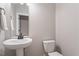 Clean and modern half bathroom featuring a pedestal sink, toilet, and neutral color scheme at 105 Blue Prince Trl, Holly Springs, NC 27540