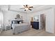 Comfortable main bedroom featuring a tray ceiling, ceiling fan, ensuite bathroom and natural light at 105 Blue Prince Trl, Holly Springs, NC 27540