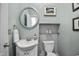 Powder room with a unique round mirror, white vanity, and tiled accent wall at 10523 Bedfordtown Dr, Raleigh, NC 27614