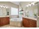 Well-lit bathroom with dual vanities, a soaking tub, and tiled flooring at 10523 Bedfordtown Dr, Raleigh, NC 27614