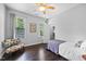 A comfortable bedroom features hardwood floors, two windows, and a cozy reading chair at 10523 Bedfordtown Dr, Raleigh, NC 27614