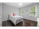A bedroom with a cozy double bed with hardwood floors and two windows at 10523 Bedfordtown Dr, Raleigh, NC 27614