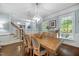 Light-filled dining room with a large wooden table, chandelier, and staircase access, blending elegance and functionality at 10523 Bedfordtown Dr, Raleigh, NC 27614