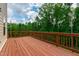 A spacious outdoor wood deck with brown painted rails is surrounded by trees and nature at 1101 Boxcar Way, Apex, NC 27502