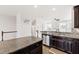 View of the kitchen's granite counters, stainless sink and appliances, dark wood cabinetry and open floor plan at 1101 Boxcar Way, Apex, NC 27502