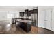 Open kitchen featuring a large island, stainless steel appliances, and sleek dark cabinets at 1101 Boxcar Way, Apex, NC 27502