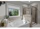 Luxurious bathroom with soaking tub, tiled shower, and a large window with a nature view at 1103 Capstone Dr, Durham, NC 27713