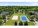 Aerial view showcasing a community park with tennis and volleyball courts near a serene lake at 1104 Dominion Hill Dr, Cary, NC 27519