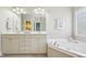 Bright bathroom boasts a double vanity, large mirror, soaking tub with tiled surround, and elegant fixtures at 1104 Dominion Hill Dr, Cary, NC 27519